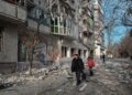 Ουκρανοί προσπερνούν κατεστραμμένο κτίριο κατοικιών μετά από ολονύχτιες ρίψεις ρουκετών στη Χερσώνα (φωτ. EPA/Maria Senovilla)