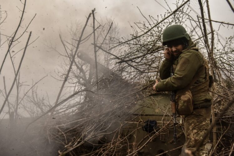 Ουκρανός στρατιώτης στέκεται δίπλα σε άρμα μάχης που ρίχνει βολή έξω από το Μπαχμούτ, στην επαρχία του Ντόνετσκ (φωτ.: EPA/Oleg Petrasyuk)