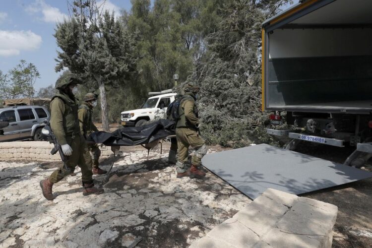 Ισραηλινοί στρατιώτες μεταφέρουν σορούς ομοεθνών τους που σκοτώθηκαν στο κιμπούτζ Κφαρ Αζά, στα σύνορα με τη Γάζα (φωτ.: EPA/ ATEF SAFADI)