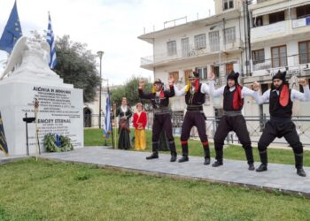 Πυρριχιστές αποδίδουν το χορό σέρρα δίπλα στο μνημείο που βρίσκεται στο Άργος, στην Πλατεία Δημοκρατίας (φωτ.: ΑΠΕ-ΜΠΕ / Ευάγγελος Μπουγιώτης)