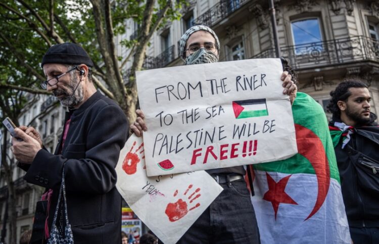 Διαδηλωτής υπέρ των Παλαιστινίων κρατά πανό που αναγράφει «Από το ποτάμι ως τη θάλασσα η Παλαιστίνη θα ελευθερωθεί», στη διάρκεια διαμαρτυρίας στο Παρίσι κατά των ισραηλινών βομβαρδισμών στη Λωρίδα της Γάζας (φωτ.: EPA/Christophe Petit Tesson)
