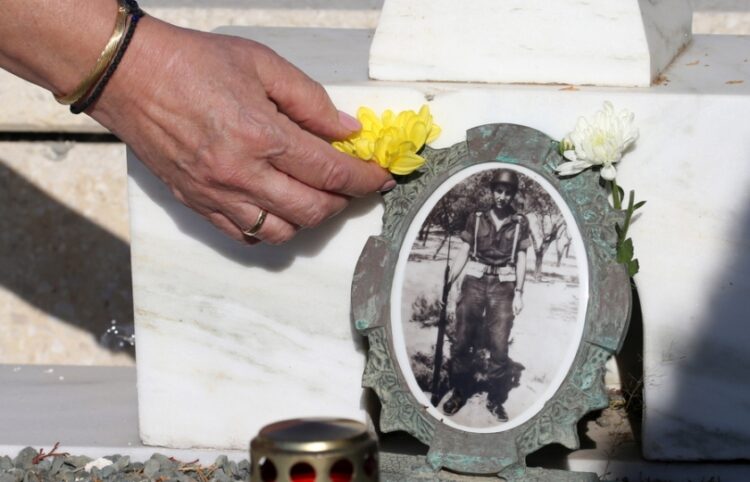 Γυναίκα στα κοιμητήρια στον Τύμβο της Μακεδονίτισσας τοποθετεί ένα λουλούδι δίπλα στη φωτογραφία στρατιώτη που έχασε τη ζωή του κατά την τουρκική εισβολή στην Κύπρο το 1974 (φωτ.: ΕΡΑ / Κάτια Χριστοδούλου)