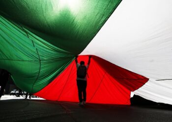 Άνδρας κάτω από μια τεράστια παλαιστινιακή σημαία (φωτ.: EPA / Elvis Gonzalez)