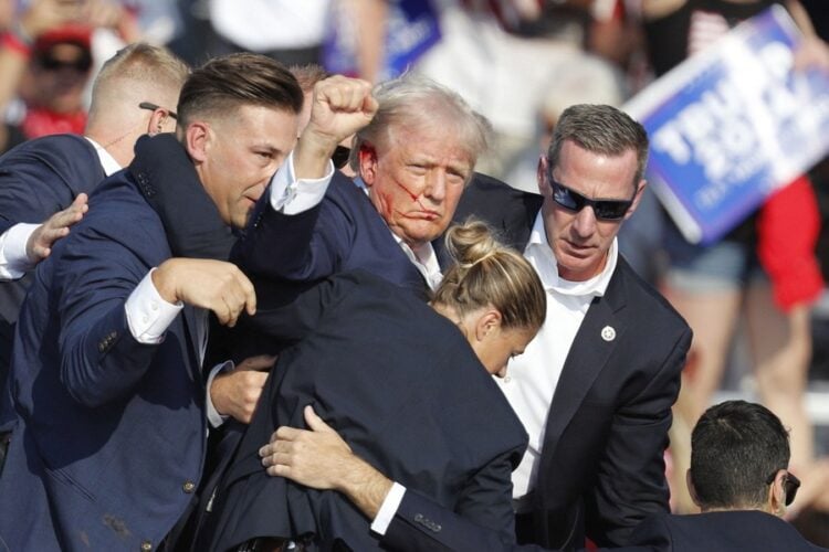 Ο Ντόναλντ Τραμπ απομακρύνεται από το πόντιουμ από άνδρες και γυναίκες της Μυστικής Υπηρεσίας του FBI, μετά την επίθεση εναντίον του στην Πενσιλβάνια κατά τη διάρκεια προεκλογικής ομιλίας (φωτ.: EPA/DAVID MAXWELL)
