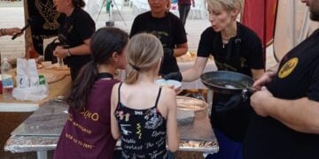 Δύο κοριτσάκια δοκιμάζουν ποντιακές γεύσεις στο «7ο Έτος Ποντιακής Γαστρονομίας», στην πλατεία του Θρυλορίου (φωτ.: facebook / Πολιτιστικός Σύλλογος Ποντίων Θρυλορίου «Η Κερασούντα & το Γαρς»)