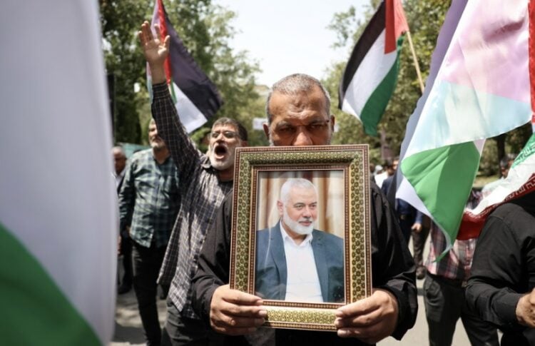 Ιρανοί κρατούν φωτογραφία του Ισμαήλ Χανίγια και παλαιστινιακές σημαίες, στη διάρκεια διαδήλωσης στην Τεχεράνη για τη δολοφονία του πολιτικού ηγέτη της Χαμάς (φωτ.: EPA/Abedin Taherkenareh)