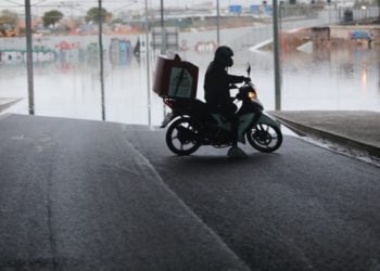 Διανομέας κάνει αναστροφή με το μηχανάκι τους μπροστά από τη γέφυρα όπου ένα λεωφορείο εγκλωβίστηκε και «βούλιαξε» στο νερό που συγκεντρώθηκε, στο ύψος του Δέλτα Φαλήρου από την κακοκαιρία «Μπάλλος» (φωτ.: 
ΑΠΕ-ΜΠΕ/ΓΙΩΡΓΟΣ ΒΙΤΣΑΡΑΣ)