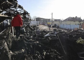 Γυναίκα στην πόλη Shevchenkove της περιοχής του Χαρκόβου, περπατά δίπλα σε κρατήρα που δημιουργήθηκε από ρωσικό βομβαρδισμό (Φωτ.: EPA/Sergey Kozlov)