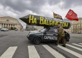 Ένας Ρώσος μπαίνει στο αυτοκίνητό του, το οποίο έχει τοποθετημένο στην οροφή έναν ψεύτικο ρωσικό πύραυλο «Sarmat», τη σημαία της Σοβιετικής Ένωσης και την επιγραφή στα ρωσικά «Ας επιστρέψουμε τις αποστολές πτήσης για πυραύλους στην Ουάσιγκτον», με αφορμή τους εορτασμούς της Πρωτομαγιάς στο κέντρο της Μόσχας (φωτ.: EPA/Sergei Ilnitsky)