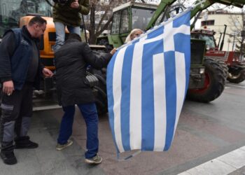 Αγρότες κρατάνε την ελληνική σημαία κατά τη διάρκεια της συμμετοχής τους σε μπλόκο στην κεντρική πλατεία Λάρισας (φωτ.: ΑΠΕ-ΜΠΕ/Αποστόλης Ντόμαλης)