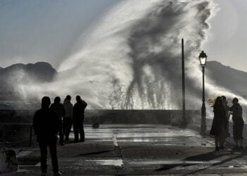 Κόσμος απολαμβάνει τη θέα από τα κύματα που χτυπούν σε προβλήτα στο Λουτράκι (φωτ.: ΑΠΕ-ΜΠΕ / Βασίλης Ψωμάς)