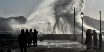 Κόσμος απολαμβάνει τη θέα από τα κύματα που χτυπούν σε προβλήτα στο Λουτράκι (φωτ.: ΑΠΕ-ΜΠΕ / Βασίλης Ψωμάς)