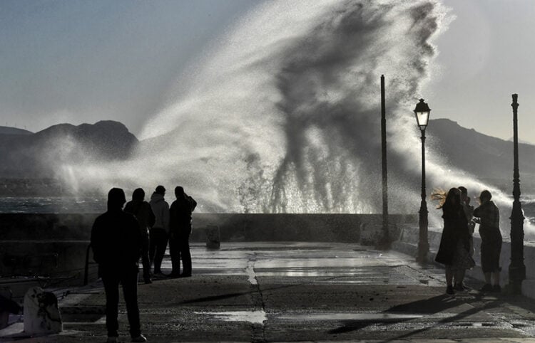 Κόσμος απολαμβάνει τη θέα από τα κύματα που χτυπούν σε προβλήτα στο Λουτράκι (φωτ.: ΑΠΕ-ΜΠΕ / Βασίλης Ψωμάς)