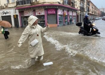 Γυναίκα βγάζει φωτογραφία σε πλημμυρισμένο δρόμο της Μάλαγα, η οποία είναι σε κόκκινο συναγερμό λόγω εξαιρετικά έντονης βροχόπτωσης (φωτ.: EPA/Maria Alonso)