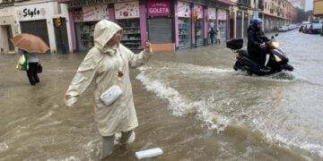 Γυναίκα βγάζει φωτογραφία σε πλημμυρισμένο δρόμο της Μάλαγα, η οποία είναι σε κόκκινο συναγερμό λόγω εξαιρετικά έντονης βροχόπτωσης (φωτ.: EPA/Maria Alonso)