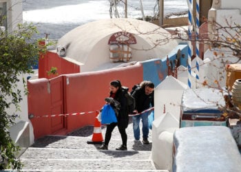 Πολίτες περνούν κορδέλα της αστυνομίας σε αποκλεισμένο σοκάκι στην Οία που έχει σχεδόν αδειάσει από τουρίστες και μόνιμους κατοίκους (φωτ.: ΑΠΕ-ΜΠΕ / Ορέστης Παναγιώτου)