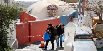 Πολίτες περνούν κορδέλα της αστυνομίας σε αποκλεισμένο σοκάκι στην Οία που έχει σχεδόν αδειάσει από τουρίστες και μόνιμους κατοίκους (φωτ.: ΑΠΕ-ΜΠΕ / Ορέστης Παναγιώτου)