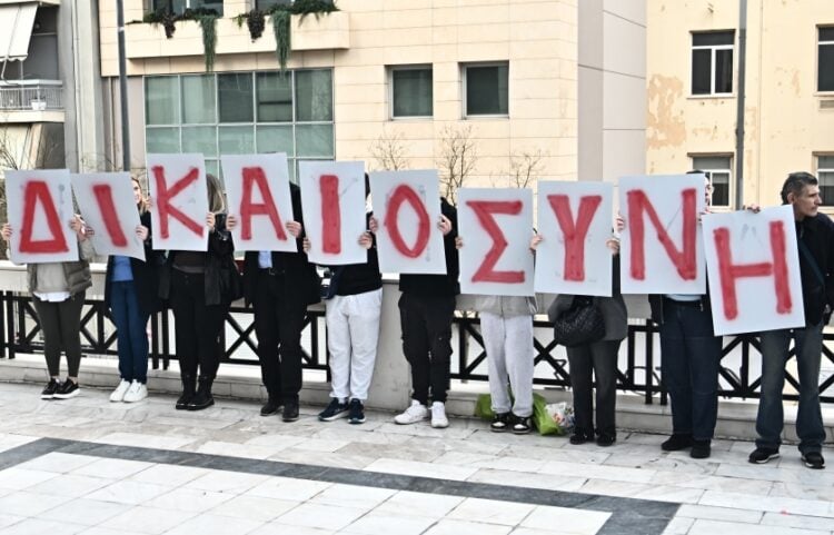 Συγγενείς των θυμάτων κρατούν πανό με τα γράμματα που σχηματίζουν τη λέξη «δικαιοσύνη» έξω από το εφετείο (φωτ.: EUROKINISSI/Κώστας Τζούμας)